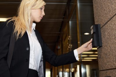 An image of a women pressing an Access Control System to open a door