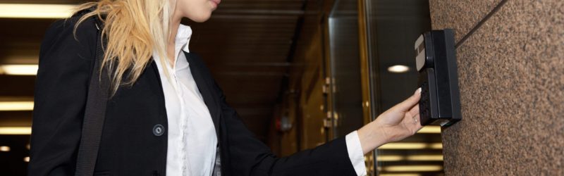 An image of a women pressing an Access Control System to open a door