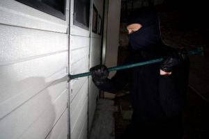 An image of a burglar trying to break entry into a locked building