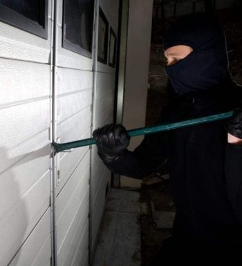 An image of a burglar trying to break entry into a locked building