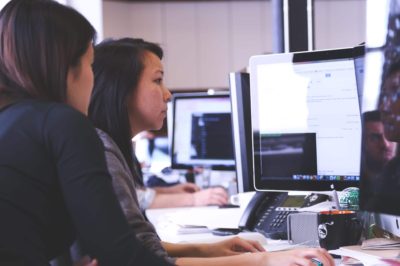 An image of two employees looking at a computer which is monitored by workplace security