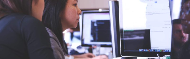 An image of two employees looking at a computer which is monitored by workplace security