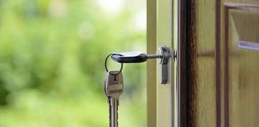 An image of an open front door of a house, with a key inside a lock.